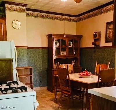 134 E Summit St, Alliance, OH 44601 - dining area featuring wainscoting, ornamental molding, a ceiling fan, light tile patterned flooring, and wallpapered walls