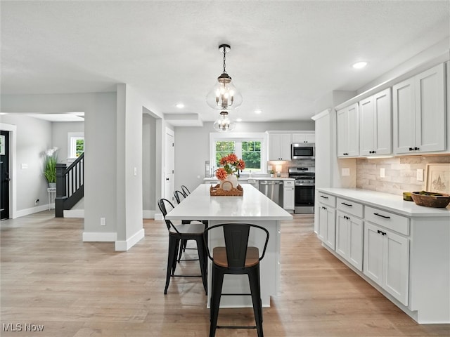 4930 S Ridge Rd W, Ashtabula, OH 44004 - kitchen with stainless steel appliances, a kitchen breakfast bar, decorative backsplash, light countertops, and white cabinets