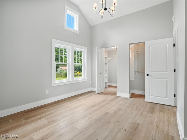 4930 S Ridge Rd W, Ashtabula, OH 44004 - unfurnished bedroom featuring high vaulted ceiling, a chandelier, light wood finished floors, and multiple closets