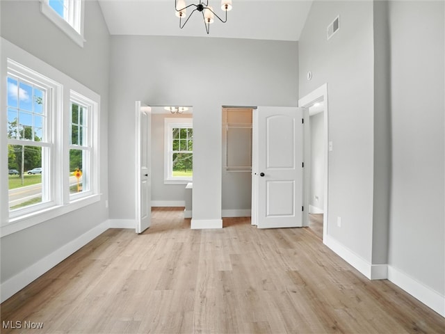 4930 S Ridge Rd W, Ashtabula, OH 44004 - unfurnished bedroom with a chandelier, a towering ceiling, light wood-style flooring, and a closet