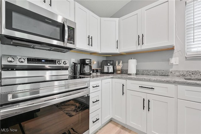 4933 Lear Nagle Rd, North Ridgeville, OH 44039 - kitchen featuring appliances with stainless steel finishes, white cabinetry, light stone counters, and light wood-style floors
