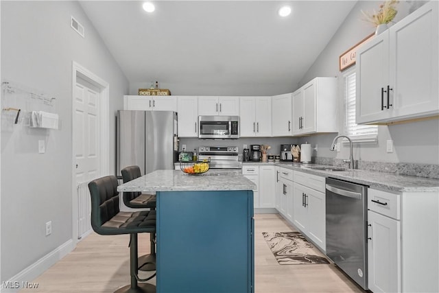 4933 Lear Nagle Rd, North Ridgeville, OH 44039 - kitchen featuring stainless steel appliances, lofted ceiling, a kitchen breakfast bar, recessed lighting, and light stone countertops
