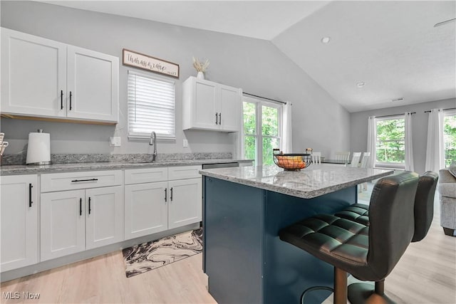 4933 Lear Nagle Rd, North Ridgeville, OH 44039 - kitchen featuring light wood-style floors, lofted ceiling, a breakfast bar area, plenty of natural light, and white cabinetry
