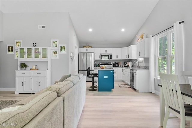 4933 Lear Nagle Rd, North Ridgeville, OH 44039 - kitchen with appliances with stainless steel finishes, open floor plan, a kitchen breakfast bar, light wood-type flooring, and white cabinets