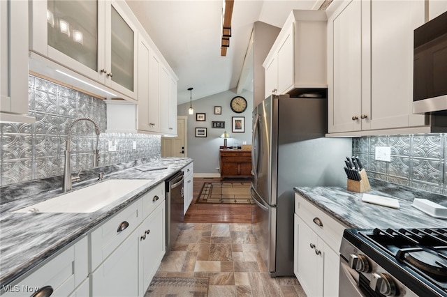 25171 Doe Dr, North Olmsted, OH 44070 - kitchen with lofted ceiling, appliances with stainless steel finishes, decorative backsplash, white cabinets, and light stone counters