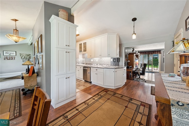 25171 Doe Dr, North Olmsted, OH 44070 - kitchen featuring stainless steel dishwasher, hardwood / wood-style floors, vaulted ceiling, white cabinets, and tasteful backsplash