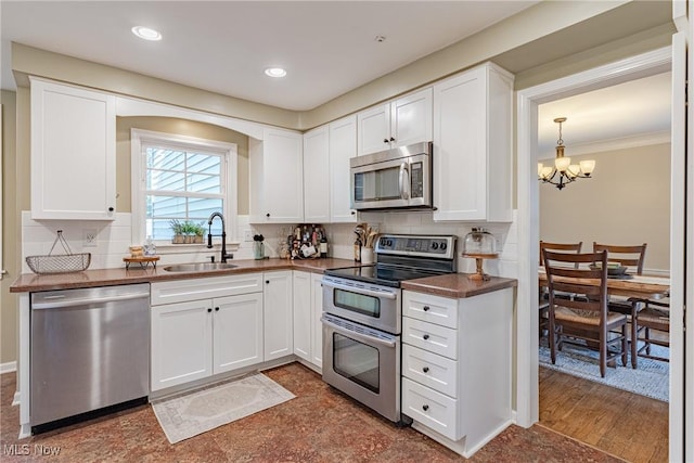 2383 Saybrook Rd, University Heights, OH 44118 - kitchen featuring stainless steel appliances, a chandelier, white cabinets, backsplash, and ornamental molding