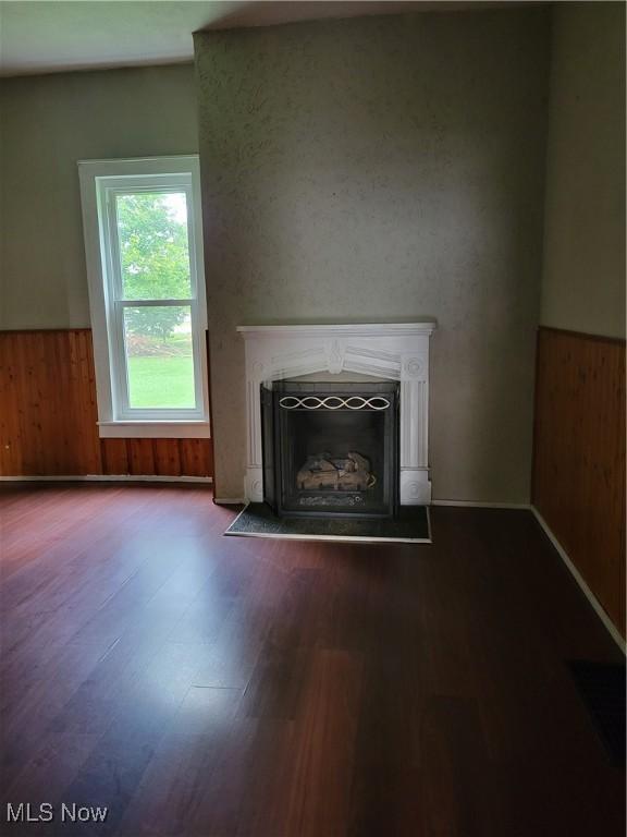217 E 4th St, Warsaw, OH 43844 - unfurnished living room with a wainscoted wall, a fireplace with flush hearth, wood finished floors, and wooden walls