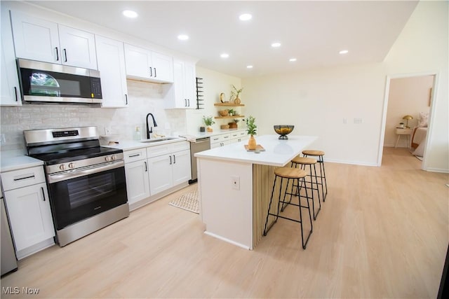 7142 N Oxshire Pl, Concord, OH 44077 - kitchen featuring appliances with stainless steel finishes, a breakfast bar area, light wood finished floors, backsplash, and recessed lighting