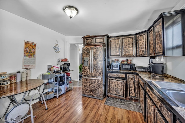 29100 Weber Ave, Wickliffe, OH 44092 - kitchen featuring stainless steel fridge with ice dispenser, black microwave, light wood-style flooring, arched walkways, and dark brown cabinetry