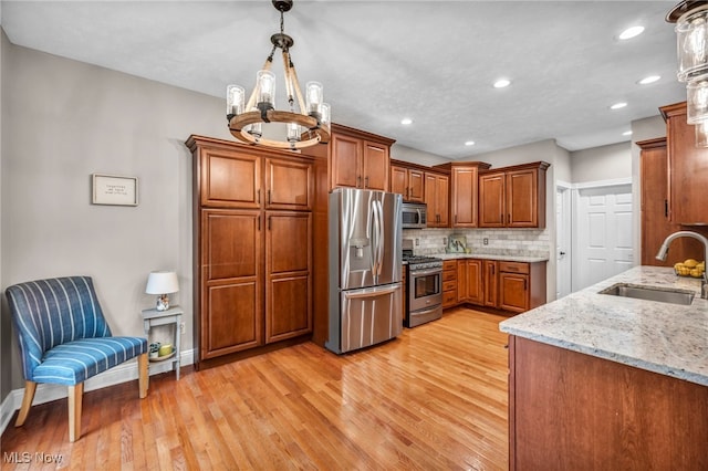 7955 Forest Valley Ln, Concord, OH 44077 - kitchen featuring stainless steel appliances, brown cabinets, light wood-style floors, decorative backsplash, and light stone counters