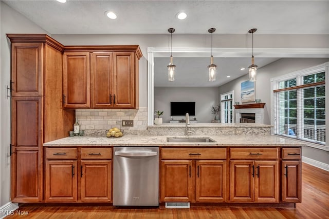 7955 Forest Valley Ln, Concord, OH 44077 - kitchen featuring dishwasher, wood finished floors, brown cabinets, light stone countertops, and a fireplace