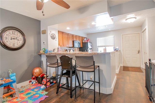 2262 Pine Top Ct Unit 31, Akron, OH 44319 - kitchen with black microwave, freestanding refrigerator, a kitchen bar, dark wood-style floors, and recessed lighting