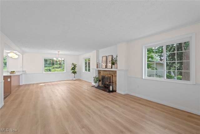 3695 S Hametown Rd, Norton, OH 44203 - unfurnished living room featuring light wood-style floors, plenty of natural light, a chandelier, a textured ceiling, and a fireplace with flush hearth