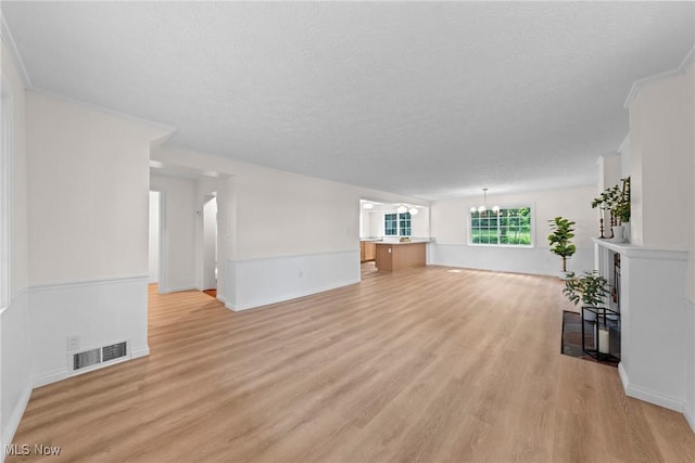 3695 S Hametown Rd, Norton, OH 44203 - unfurnished living room with a chandelier, light wood-style floors, a textured ceiling, a wainscoted wall, and crown molding