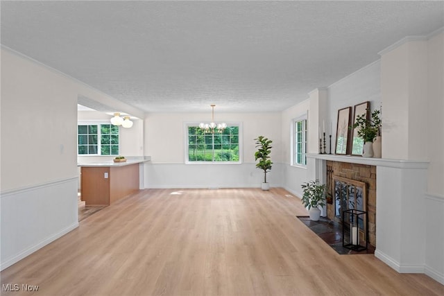 3695 S Hametown Rd, Norton, OH 44203 - unfurnished living room featuring light wood-style flooring, a chandelier, a textured ceiling, and a fireplace with flush hearth
