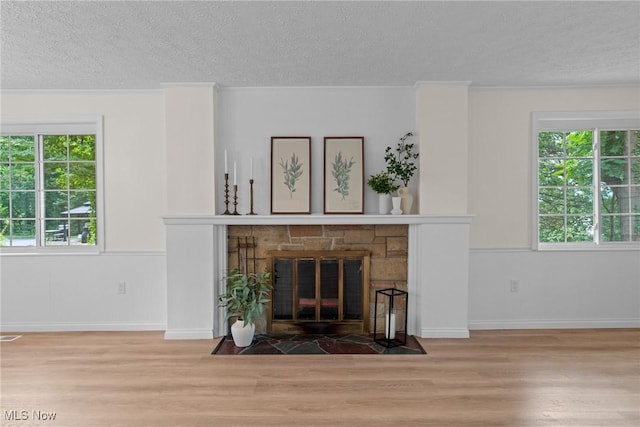 3695 S Hametown Rd, Norton, OH 44203 - unfurnished living room with a textured ceiling, wood finished floors, a stone fireplace, and crown molding