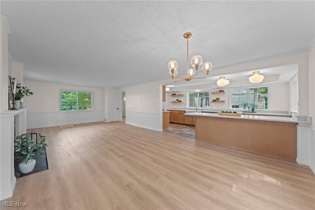 3695 S Hametown Rd, Norton, OH 44203 - unfurnished living room featuring a textured ceiling, light wood-type flooring, a chandelier, and wainscoting