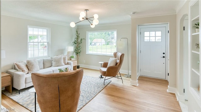 22100 Priday Ave, Euclid, OH 44123 - living room featuring crown molding, healthy amount of natural light, light wood-style floors, and a chandelier
