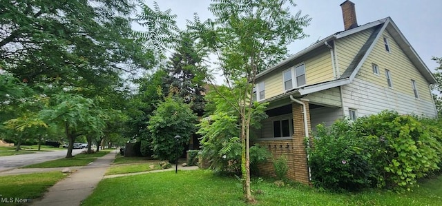 3624 E 154th St, Cleveland, OH 44120 - view of home's exterior featuring a chimney, brick siding, and a yard