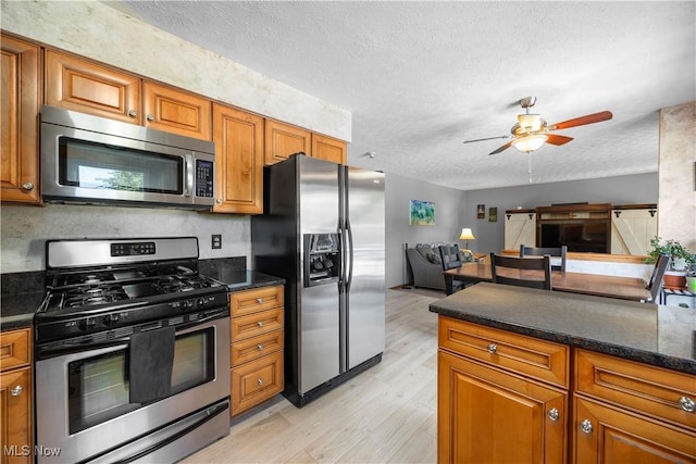 23730 Sawmill Bnd, Olmsted Falls, OH 44138 - kitchen featuring stainless steel appliances, brown cabinetry, light wood finished floors, a ceiling fan, and a textured ceiling