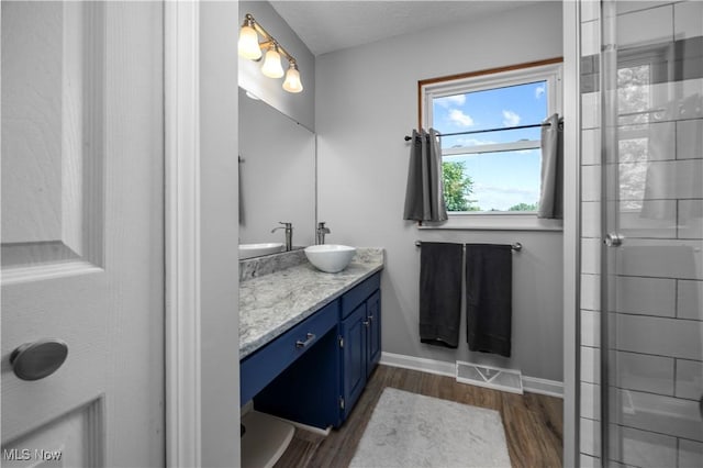23730 Sawmill Bnd, Olmsted Falls, OH 44138 - bathroom featuring double vanity, wood finished floors, and a shower with shower door