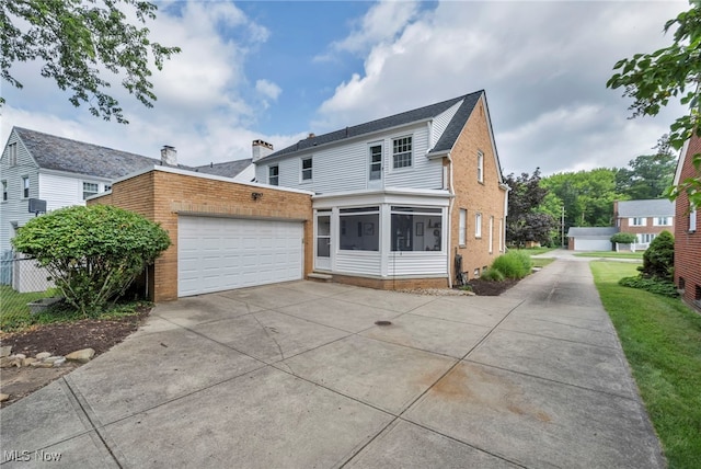 9013 Elsmere Dr, Parma, OH 44130 - back of house with brick siding, concrete driveway, an attached garage, and a sunroom