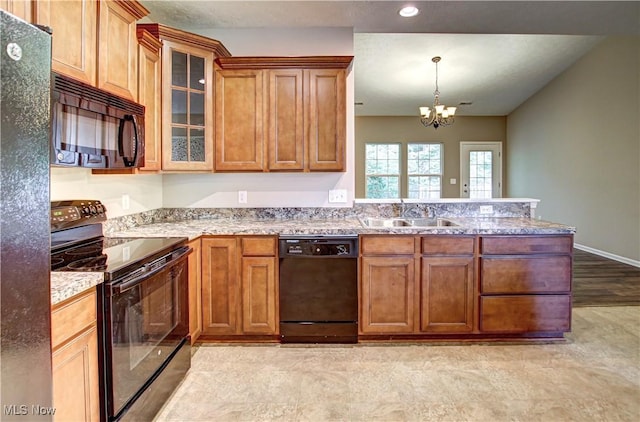 9111 Devonshire Dr, Olmsted Falls, OH 44138 - kitchen featuring black appliances, a peninsula, brown cabinets, a chandelier, and light stone counters
