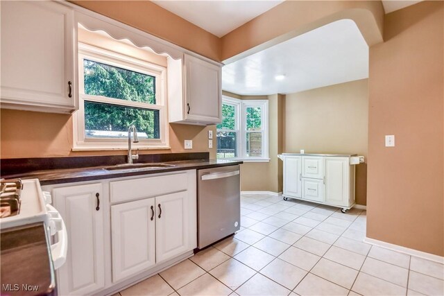 2607 Ashurst Rd, University Heights, OH 44118 - kitchen featuring stainless steel dishwasher, dark countertops, white cabinets, light tile patterned floors, and stove