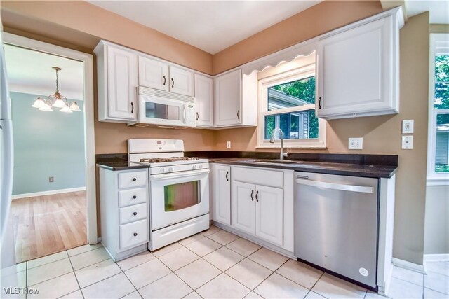 2607 Ashurst Rd, University Heights, OH 44118 - kitchen featuring white appliances, dark countertops, white cabinetry, a chandelier, and light tile patterned flooring