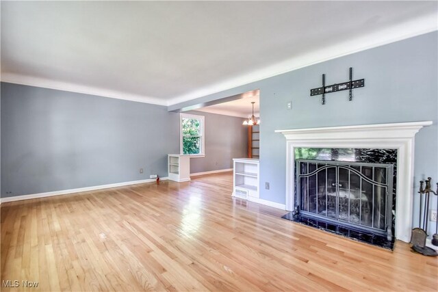 2607 Ashurst Rd, University Heights, OH 44118 - unfurnished living room with wood finished floors, a fireplace, and a chandelier