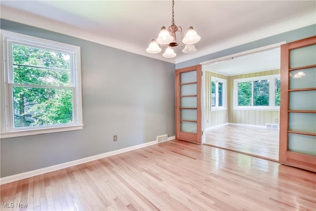 2607 Ashurst Rd, University Heights, OH 44118 - empty room featuring a chandelier, healthy amount of natural light, and wood finished floors