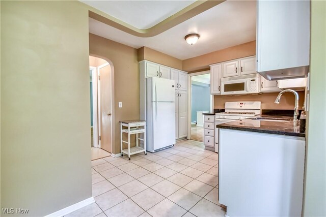 2607 Ashurst Rd, University Heights, OH 44118 - kitchen with white appliances, arched walkways, white cabinets, and light tile patterned floors