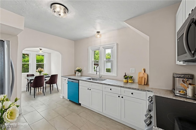 3497 Raymont Blvd, University Heights, OH 44118 - kitchen with stainless steel appliances, arched walkways, light stone countertops, and white cabinetry