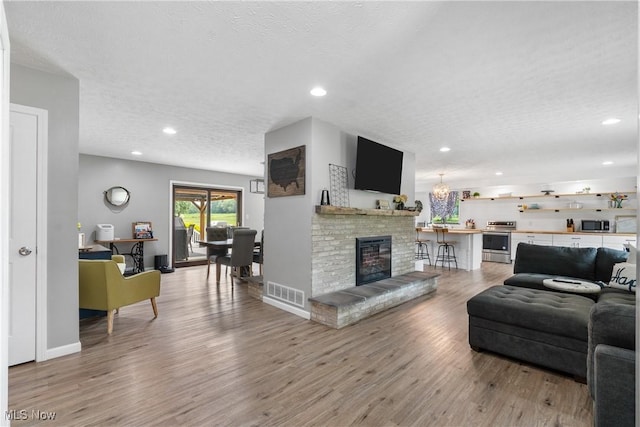 3111 Serfass Rd, New Franklin, OH 44216 - living room with a textured ceiling, light wood finished floors, a brick fireplace, and recessed lighting