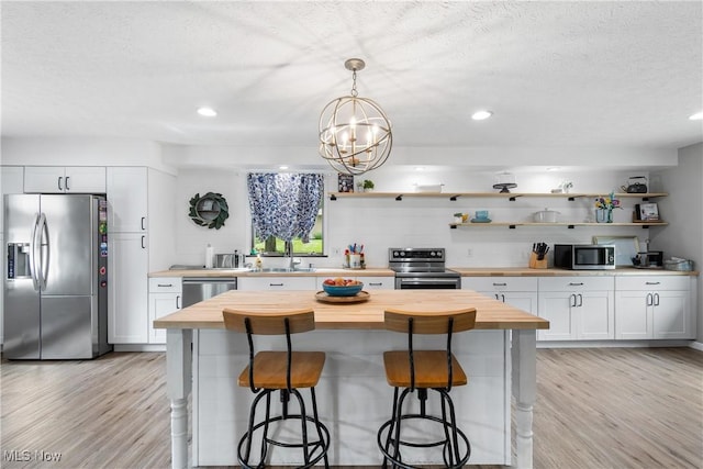 3111 Serfass Rd, New Franklin, OH 44216 - kitchen featuring appliances with stainless steel finishes, butcher block countertops, open shelves, light wood-style flooring, and a textured ceiling