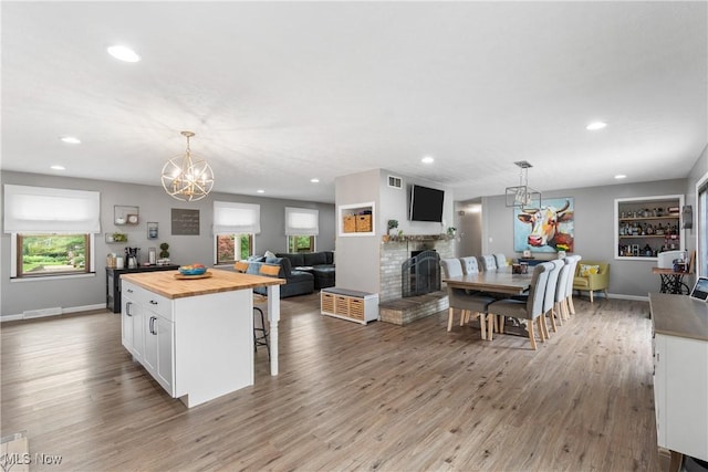 3111 Serfass Rd, New Franklin, OH 44216 - kitchen with butcher block counters, wood finished floors, white cabinets, recessed lighting, and a fireplace with raised hearth