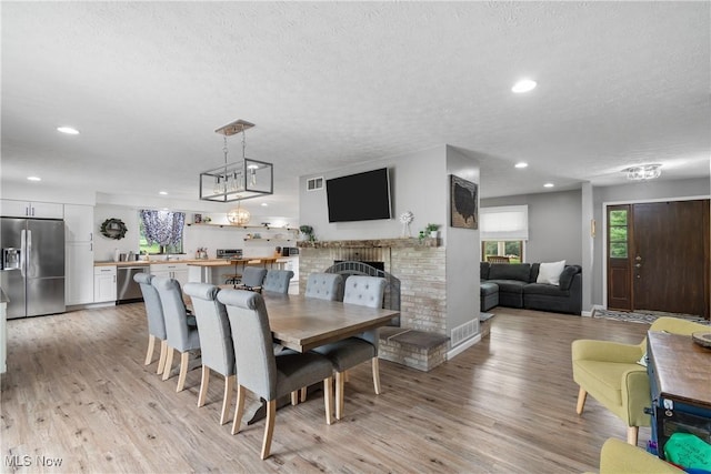 3111 Serfass Rd, New Franklin, OH 44216 - dining area featuring a textured ceiling, light wood finished floors, recessed lighting, and a brick fireplace
