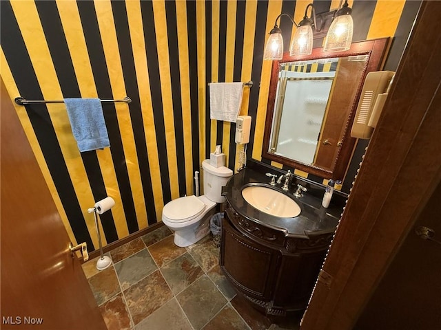 1208 3rd St NW, New Philadelphia, OH 44663 - full bath featuring stone tile flooring, wallpapered walls, vanity, and a shower with shower door