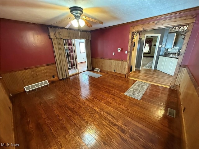 1208 3rd St NW, New Philadelphia, OH 44663 - spare room featuring a wainscoted wall, a ceiling fan, wood finished floors, and wooden walls