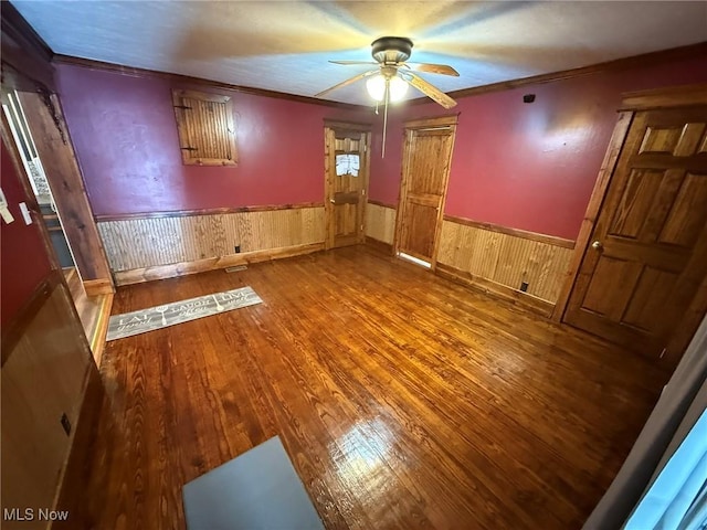 1208 3rd St NW, New Philadelphia, OH 44663 - unfurnished room with a ceiling fan, wood finished floors, wainscoting, ornamental molding, and wood walls