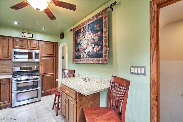 1433 Raleigh Blvd, Copley, OH 44321 - kitchen featuring stainless steel appliances, arched walkways, decorative backsplash, ceiling fan, and recessed lighting