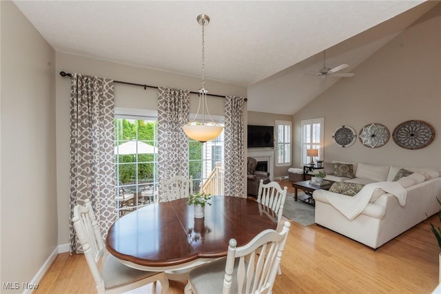 23450 Wainwright Ter, Olmsted Falls, OH 44138 - dining space with a ceiling fan, light wood-style floors, a fireplace, and vaulted ceiling