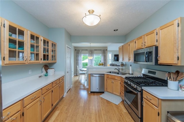 23450 Wainwright Ter, Olmsted Falls, OH 44138 - kitchen featuring stainless steel appliances, light wood-style flooring, a peninsula, light countertops, and a textured ceiling