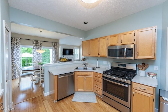 23450 Wainwright Ter, Olmsted Falls, OH 44138 - kitchen with stainless steel appliances, a peninsula, light wood-style flooring, light countertops, and a textured ceiling