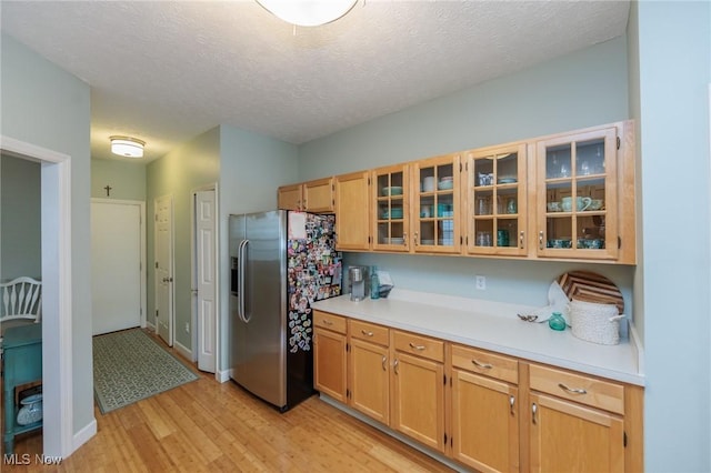 23450 Wainwright Ter, Olmsted Falls, OH 44138 - kitchen featuring stainless steel refrigerator with ice dispenser, light wood finished floors, light countertops, glass insert cabinets, and a textured ceiling