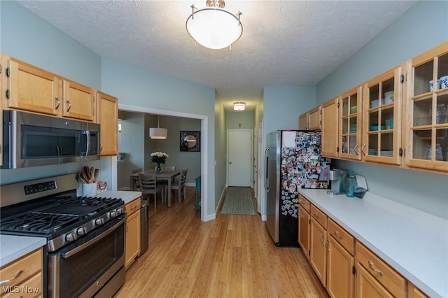 23450 Wainwright Ter, Olmsted Falls, OH 44138 - kitchen featuring appliances with stainless steel finishes, light countertops, light wood-style flooring, glass insert cabinets, and a textured ceiling