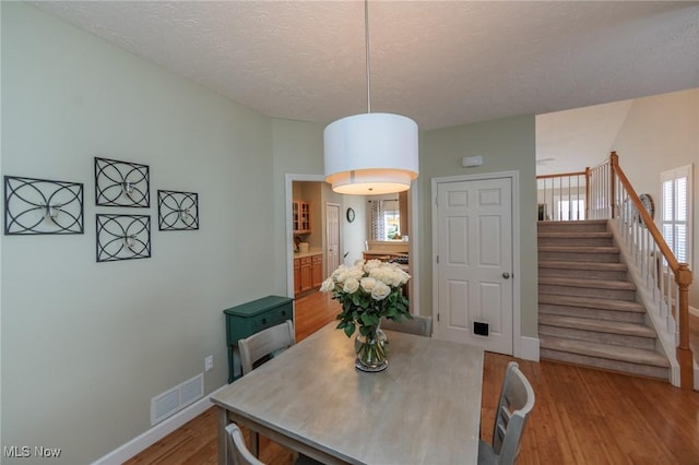 23450 Wainwright Ter, Olmsted Falls, OH 44138 - dining area featuring light wood-type flooring, stairway, and a textured ceiling