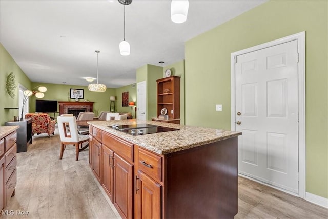 1103 Greenmont Cir, Vienna, WV 26105 - kitchen featuring black electric cooktop, light wood finished floors, a fireplace, a center island, and pendant lighting