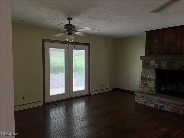 100 Crestview Dr, Newcomerstown, OH 43832 - unfurnished living room with baseboard heating, a ceiling fan, dark wood finished floors, a textured ceiling, and a stone fireplace
